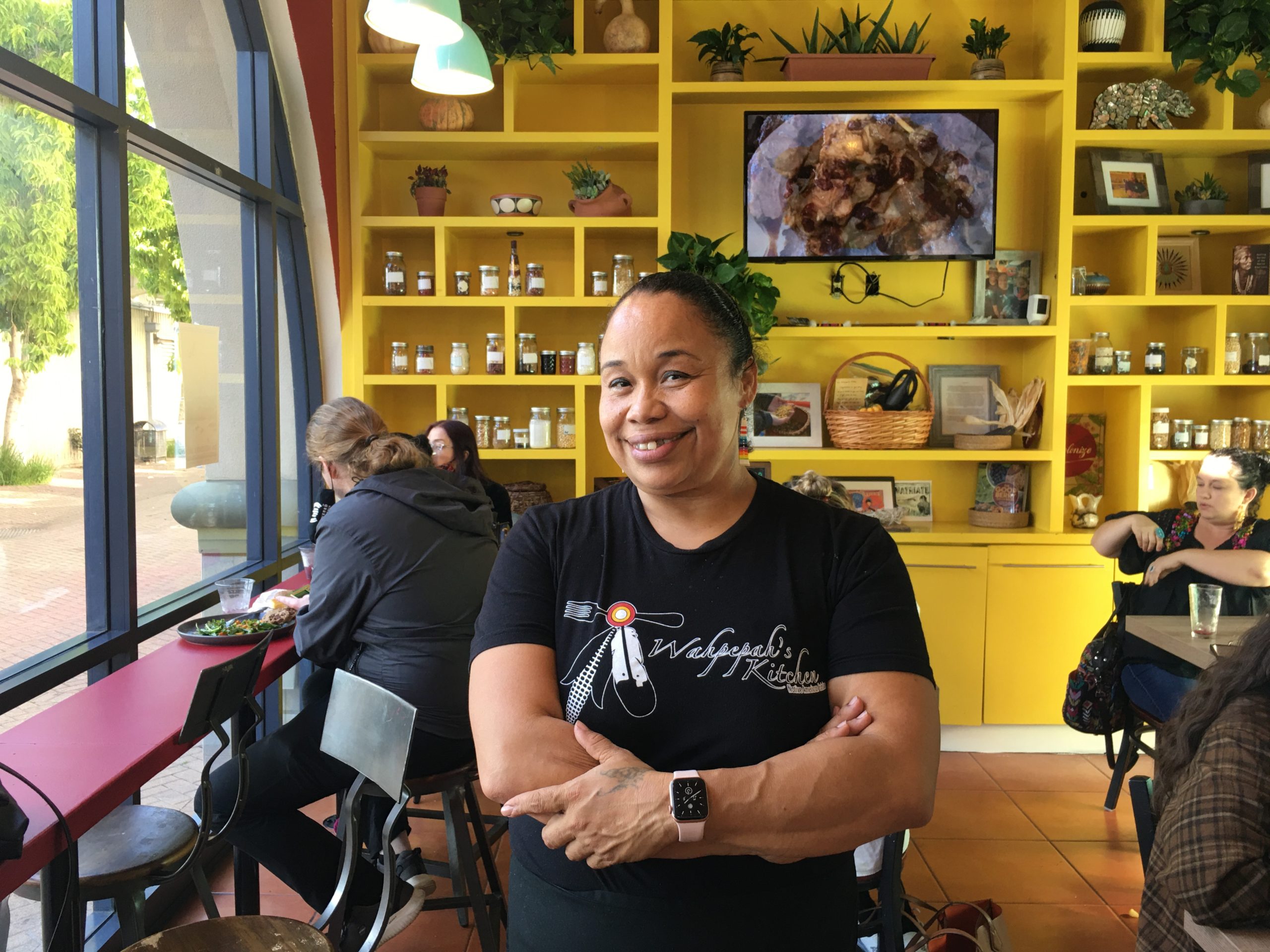 A woman in a black t-shirt posing inside a brightly-colored restaurant